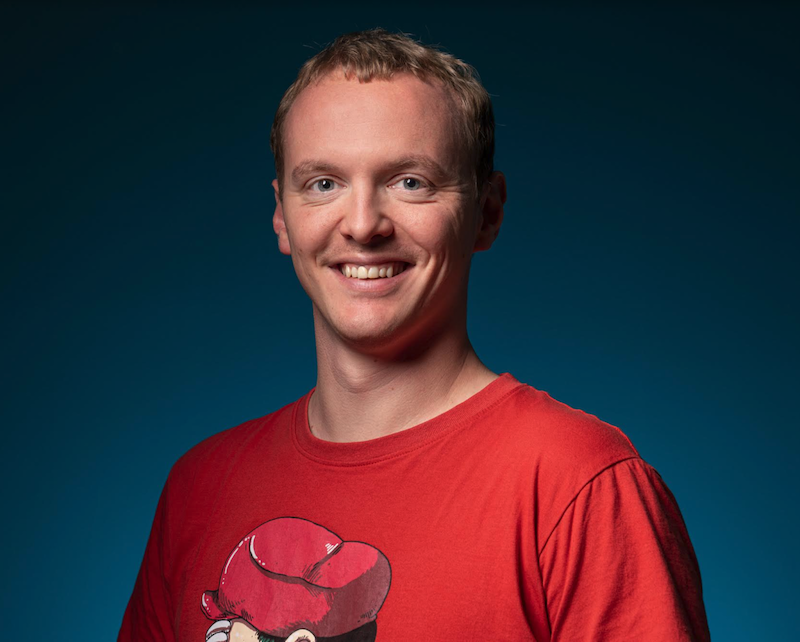 Portrait of Christoph Bühler in a red shirt on blue background.